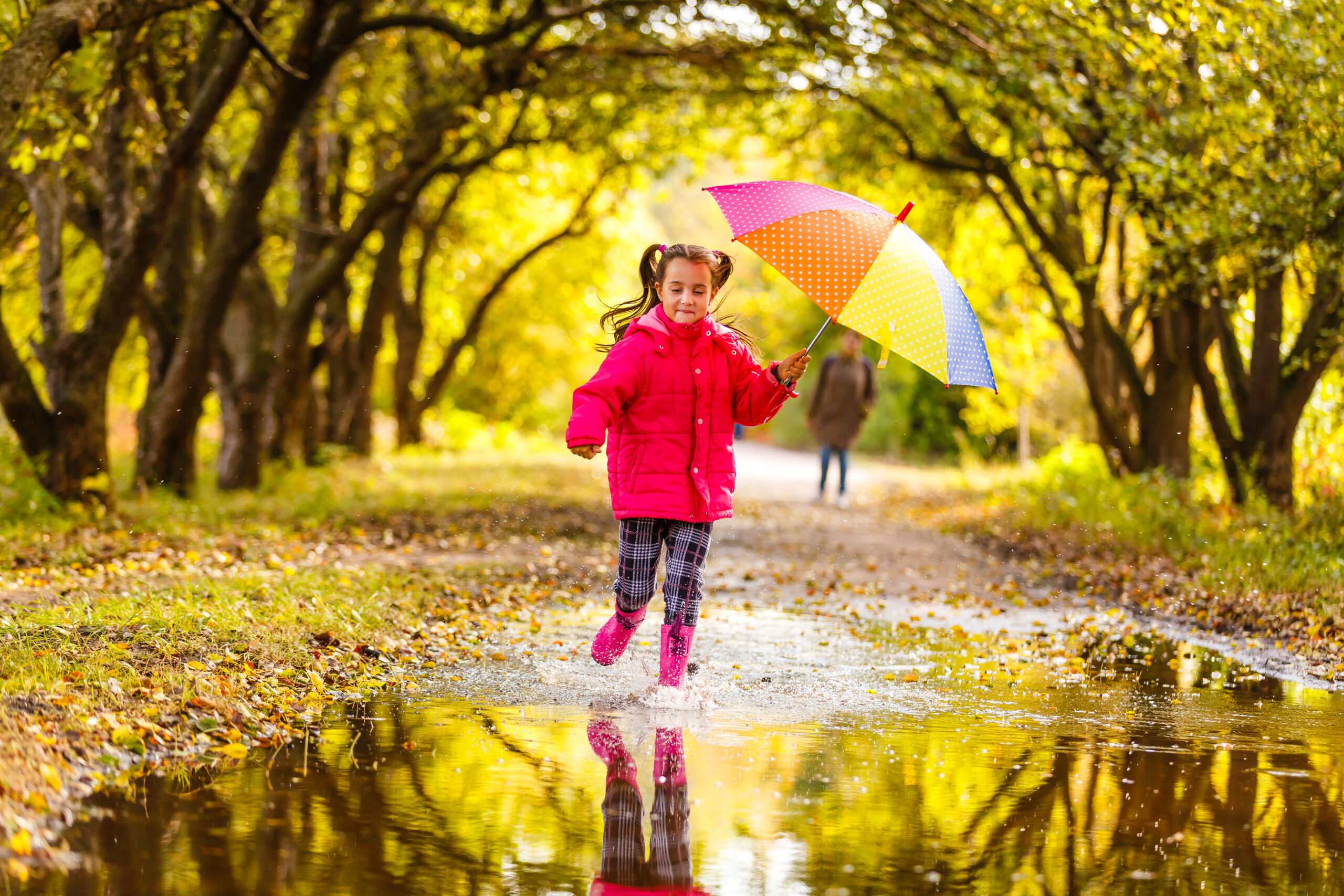 Girl splashing in a puddle with a colourful umbrella