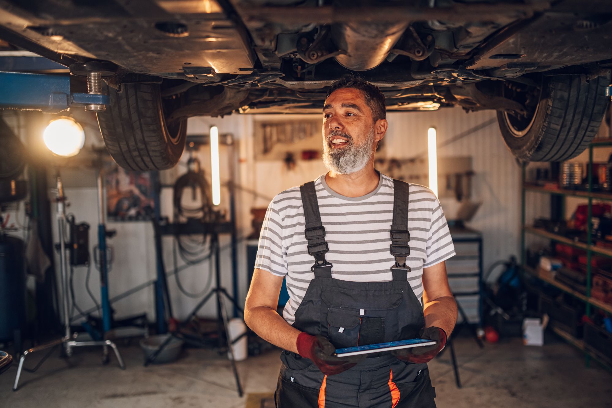 Happy mechanic at his workshop with a tablet