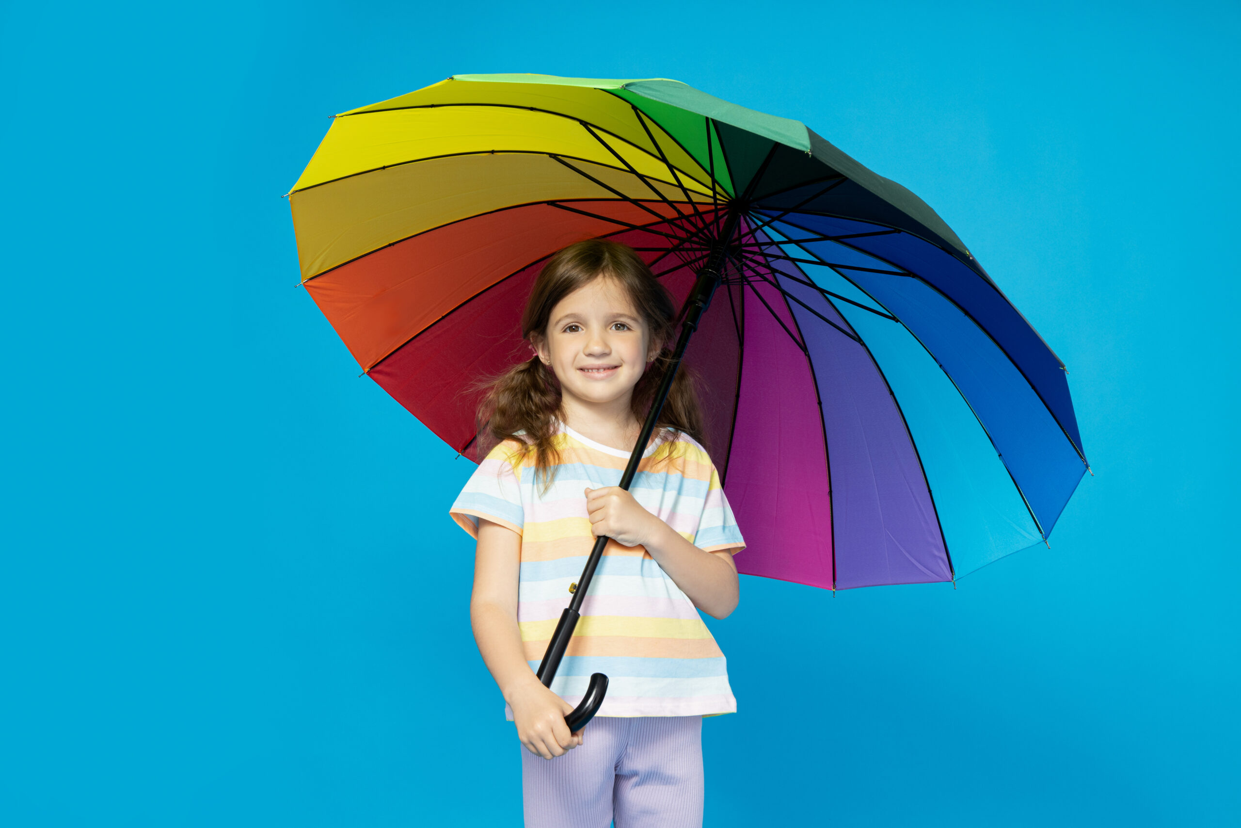 Smiling girl holding a rainbow umbrella